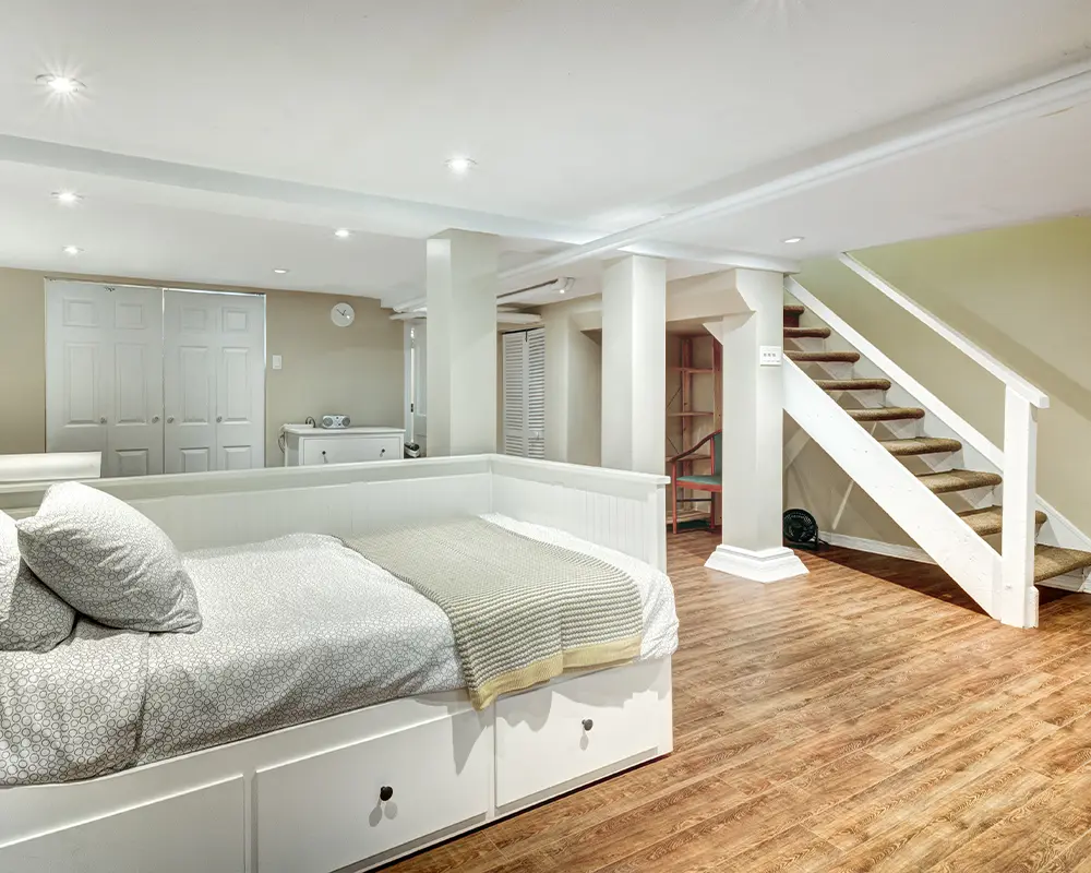 Bright basement bedroom with white storage bed, wood floors, and a cozy ambiance.