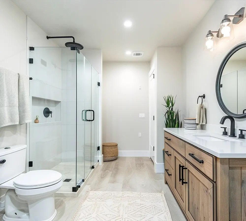 Modern bathroom remodel with glass-enclosed shower and natural wood vanity.